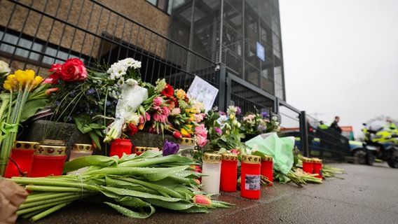 Flowers and candles lie and stand in front of the entrance to a church of Jehovah's Witnesses in the Alsterdorf district. © dpa Photo: Christian Charisius
